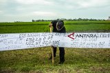 Warga memasang kain bertuliskan aksara sunda saat pemecahan Original Rekor Indonesia (ORI) di Batujaya, Karawang, Jawa Barat, Jumat (21/9). Penulisan aksara sunda sepanjang 385 meter berhasil memecahkan rekor ORI yang bertujuan untuk melestarikan aksara sunda di Indonesia. ANTARA JABAR/M Ibnu Chazar/agr/18.