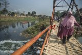 Warga melintas di Sungai Cikapundung di Bojongsoang, Kabupaten Bandung, Jawa Barat, Rabu (26/9). Pemerintah Jawa Barat bersama Satgas Citarum Harum berencana menjadikan sejumlah titik Daerah aliran Sungai Citarum sebagai kawasan ikonis, ruang publik, ruang budaya dan wisata air dalam program normalisasi Sungai Citarum. ANTARA JABAR/Novrian Arbi/agr/18.
