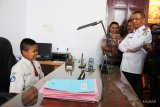 Gubernur Kalbar, Sutarmidji (kanan) mempersilahkan siswa SD pelintas batas dua negara, Nursaka (duduk) di meja kerjanya saat pertemuan di Pendopo Rumah Rakyat di Pontianak, Senin (17/9). Sutarmidji menyatakan Ia akan mengusahakan orangtua asuh untuk Nursaka agar bisa bersekolah di Pontianak. ANTARA FOTO/Jessica Helena Wuysang/18