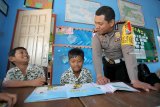 Anggota polisi mengajar di salah satu sekolah dasar negeri (SDN) di Blitar, Jawa Timur, Rabu (26/9). Polres Blitar menerjunkan personel untuk membantu proses belajar mengajar disejumlah SD hingga SMA yang sampat lumpuh sejak Senin (24/9) salu akibat aksi mogok sejumlah Guru Tidak Tetap (GTT) yang memprotes program rekrutmen CPNS 2018. Antara Jatim/Irfan Anshori/mas/18.