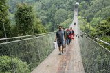 Pengunjung berjalan melintasi jembatan gantung Situ Gunung di Taman Nasional Gunung Gede Pangrango (TNGGP) Resort Situgunung, Kabupaten Sukabumi, Jawa Barat, Jumat (21/9). Jembatan gantung yang memiliki panjang mencapai 243 meter, lebar 2 meter dan dari permukaan tanah dan tinggi mencapai 161 meter tersebut merupakan jembatan gantung terpanjang di Asia. ANTARA JABAR/Nurul Ramadhan/agr/18