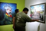 Dua pengunjung melihat dua karya lukis yang ditampilkan dalam pameran seni rupa di Taman Budaya Pontianak, Kalbar, Kamis (27/9). Pameran bertajuk Pontianak Art Exhibition yang bertema 'Colorful Khatulistiwa' itu menampilkan sejumlah karya seni dari 20 seniman Kalbar dan Malaysia. ANTARA FOTO/HS Putra/jhw/18