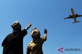 Warga menyaksikan pesawat yang akan mendarat di Bandara Sultan Hasanuddin Makassar, Sulawesi Selatan, Selasa (11/9/2018). Kementerian Perhubungan menargetkan jumlah penumpang pesawat tahun 2018 mencapai 116 juta penumpang dengan mengembangkan rute penerbangan dan membangun sejumlah bandara di Indonesia. (ANTARA FOTO/Yusran Uccang)
