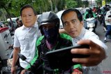 Anggota Komunitas Kuliner Binjai memakai topeng bergambar Bakal Calon Presiden Joko Widodo dan Prabowo Subianto berswafoto dengan pengemudi ojek daring di Medan, Sumatera Utara, Kamis (13/9/2018). Aksi tersebut guna menyerukan kepada masyarakat terutama pengguna sosial media untuk tidak saling hujat dan menyebarkan ujaran kebencian menjelang Pilpres 2019.  (ANTARA FOTO/Irsan Mulyadi)