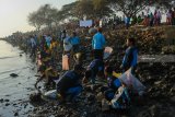 Pelajar memungut sampah saat mengikuti aksi Bersih-Bersih Pantai Jembatan Suramadu, Surabaya, Jawa Timur, Minggu (30/9). Aksi ribuan pelajar tersebut sebagai wujud kepedulian terhadap kebersihan lingkungan di kawasan yang merupakan salah satu ikon wisata di Surabaya. Antara Jatim/Didik Suhartono/mas/18.