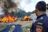 Seorang petugas menyaksikan pemusnahan bukti tekstil ilegal di Kantor Bea dan Cukai Entikong, Kabupaten Sanggau, Kalbar, Kamis (4/10). Sebanyak 682 bal seberat 10,23 ton pakaian bekas dan 1.047 gulung kain seberat 31,41 ton bahan tekstil hasil penindakan Bea Cukai Entikong dari 2009 hingga 2018 yang masuk melalui PLBN Entikong dan jalur tikus di kawasan perbatasan Indonesia-Malaysia di Kabupaten Sanggau, dimusnahkan dengan cara dibakar. ANTARA FOTO/Agus Alfian/jhw/18