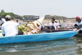 Sejumlah orang melarung tumpeng dan sesaji di Waduk Bening Kabupaten, Madiun, Jawa Timur, Minggu (7/10). Warga setempat melarung tumpeng dan sesaji ke waduk tersebut guna melestarikan tradisi untuk mengungkapkan rasa syukur kepada Tuhan yang dilakukan setiap bulan Sura dalam penanggalan Jawa bersamaan bulan Muharram. Antara Jatim/Siswowidodo/mas/18.