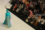 Pengunjung mengamati busana yang dikenakan seorang peragawati pada Moslem Fashion Festival di Surabaya, Jawa Timur, Jumat (12/10). Berbagai macam model busana muslim karya sejumlah perancang busana dipamerkan dalam peragaan busana yang berlangsung sampai tanggal 14 Oktober 2018 itu. Antara Jatim/Didik Suhartono/mas/18.