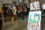 Pengunjung melihat lukisan kartun yang dipajang dalam Pameran Kartun Anti Korupsi di Balaikota Malang, Jawa Timur, Selasa (2/10). Pameran 200 karya kartun Anti Korupsi yang berlangsung selama tiga hari tersebut merupakan upaya pencegahan dan perlawanan terhadap korupsi di lingkup pemerintahan dan pelayanan publik. Antara Jatim/Ari Bowo Sucipto/mas/18.