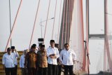 Presiden Joko Widodo (ketiga kanan) didampingi Ibu Negara Iriana Joko Widodo  (ketiga kiri), Menteri PUPR Basuki Hadimuljono (kiri), Sekretaris Kabinet Pramono Anung (kanan) dan Gubernur Jawa Timur Soekarwo (kedua kanan) serta pejabat setempat dan para ulama berada di atasi truk saat meresmikan pembebasan tarif tol Jembatan Suramadu di Surabaya, Jawa Timur, Sabtu (27/10/2018). Dengan diberlakukan pembebasan tarif tol tersebut diharapkan berdampak pada pertumbuhan ekonomi di Pulau Madura. Antara Jatim/Zabur Karuru