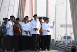 Presiden Joko Widodo (ketiga kanan) didampingi Menteri PUPR Basuki Hadimuljono (kelima kanan), Sekretaris Kabinet Pramono Anung (kanan) dan Gubernur Jawa Timur Soekarwo (kedua kanan) serta pejabat setempat dan para ulama meresmikan pembebasan tarif tol Jembatan Suramadu di atas truk di jembatan tersebut, Surabaya, Jawa Timur, Sabtu (27/10). Dengan diberlakukan pembebasan tarif tol tersebut diharapkan berdampak pada pertumbuhan ekonomi di Pulau Madura. Antara Jatim/Zabur Karuru