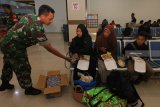 Personel TNI membagikan air minum kepada sejumlah pengungsi di Gapura Surya Nusantara, Pelabuhan Tanjung Perak, Surabaya, Jawa Timur, Selasa (9/10) malam. Sekitar 256 pengungsi korban bencana gempa dan tsunami Palu, Sulawesi Tengah, turun dari KM Labobar yang selanjutnya dilakukan pendataan serta diantarkan ke daerah tujuannya. Antara Jatim/Didik Suhartono/mas/18.