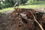 Warga melintasi lokasi pergerakan tanah di Desa Cijayanti, Babakan Madang, Bogor, Jawa Barat, Selasa (23/10/2018). Pergerakan tanah yang diakibatkan oleh curah hujan yang tinggi itu menyebabkan lubang sepanjang 150 meter dengan lebar satu meter dan sebanyak 25 rumah serta satu masjid mengalami kerusakan ringan. ANTARA JABAR/Yulius Satria Wijaya/agr.