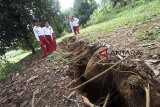 Warga melintasi lokasi pergerakan tanah di Desa Cijayanti, Babakan Madang, Bogor, Jawa Barat, Selasa (23/10/2018). Pergerakan tanah yang diakibatkan oleh curah hujan yang tinggi itu menyebabkan lubang sepanjang 150 meter dengan lebar satu meter dan sebanyak 25 rumah serta satu masjid mengalami kerusakan ringan. ANTARA JABAR/Yulius Satria Wijaya/agr.