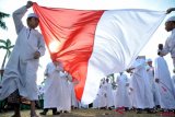 Sejumlah santri membentangkan bendera Merah Putih saat kirab memperingati Hari Santri Nasional di halaman kantor DPRD Sumsel, Palembang, Sumsel, Sabtu (20/10/2018). Sebanyak 15.000 Santri se-kota Palembang turut memeriahkan kirab yang mengambil tema 