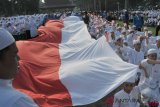     Sejumlah santri membentangkan bendera Merah Putih saat kirab memperingati Hari Santri Nasional di halaman kantor DPRD Sumsel, Palembang, Sumsel, Sabtu (20/10/2018). Sebanyak 15.000 Santri se-kota Palembang turut memeriahkan kirab yang mengambil tema 