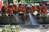 Petugas menyemprotkan air ke pipa gas yang terbakar di Jalan Ngagel Jaya Selatan, Surabaya, Jawa Timur, Jumat (26/10/2018). Sekitar empat kendaraan pemadam kebakaran dikerahkan untuk memadamkan semburan api dari pipa gas yang diduga pecah setelah terkena alat berat (back hoe) saat pengerukan endapan sungai itu. Antara Jatim/Didik Suhartono/ZK.