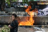 Warga menyaksikan pipa gas yang terbakar di Jalan Ngagel Jaya Selatan, Surabaya, Jawa Timur, Jumat (26/10/2018). Sekitar empat kendaraan pemadam kebakaran dikerahkan untuk memadamkan semburan api dari pipa gas yang diduga pecah setelah terkena alat berat (back hoe) saat pengerukan endapan sungai itu. Antara Jatim/Didik Suhartono/ZK.