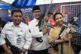 Menteri BUMN Rini Soemarno (kanan) didampingi Direktur Utama PT Pindad Abraham Mose (kiri) dan Gubernur Jawa Barat Ridwan Kamil (tengah) mengangkat senjata buatan Pindad saat pameran produk-produk inovasi karya anak bangsa di Kantor LEN, Bandung, Jawa Barat, Rabu (31/10/2018). Dalam rangka kemandirian energi dan menjaga kedaulatan negara, BUMN PT Len Industri, Biofarma, Pindad, Dahana meluncurkan produk inovasi terbaru karya anak bangsa diantaranya LenSolar,Len Rescue dan melepas produk-produk ekspor ke luar negeri. ANTARA JABAR/M Agung Rajasa/agr.
