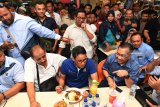 Calon Wakil Presiden Sandiaga Uno (tengah) menyantap makanan yang dijajakan di Pusat Grosir Surabaya (PGS) saat berunjung di pusat perbelanjaan itu, Surabaya, Jawa TImur, Minggu (21/10/2018). Kunjungan tersebut dalam rangka meyapa para pedagang sekaligus meninjau perekonomian di pusat perbelanjaan itu. Antara Jatim/Zabur Karuru