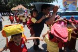 Seorang guru Sekolah Alam Insan Mulia (SAIM) menggendong muridnya sembari melindungi kepala saat mengikuti Simulasi Mitigasi Bencana di Surabaya, Jawa Timur, Rabu (24/10/2018). Simulasi yang diselenggarakan bekerja sama dengan Badan Penanggulangan Bencana Daerah (BPBD) Surabaya tersebut untuk memberikan pengetahuan dan pemahaman kepada murid mengenai mitigasi bencana. Antara Jatim/Moch Asim/ZK.