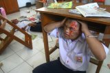Seorang siswa berkebutuhan khusus berlindung di bawah meja dalam Simulasi Penanganan bencana Gempa Bumi di Sekolah Menengah Pertama - Luar Biasa (SMPLB) Negeri, Malang, Jawa Timur, Senin (15/10). Simulasi tersebut diadakan untuk melatih kesiapan para siswa berkebutuhan khusus dan guru dalam menghadapi bencana gempa bumi. Antara Jatim/Ari Bowo Sucipto/mas/18.