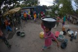 Seorang warga mengambil air bersih yang dibagikan Polres Situbondo di Desa Selowogo, Bungatan, Situbondo, Jawa Timur, Senin (1/10). Polres Situbondo menyalurkan bantuan air bersih untuk membantu warga masyarakat yang dilanda kekeringan. Antara Jatim/Seno/mas/18.