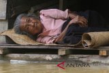 Seorang warga terbaring di teras rumahnya yang terendam banjir di Desa Pasi Leuhan, Johan Pahlawan, Aceh Barat, Aceh, Selasa (16/10/2018). Banjir yang melanda Kabupaten Aceh Singkil, Aceh Selatan, Aceh Barat Daya, Nagan Raya, Aceh Barat, Aceh Jaya, Pidie, Bireun, Aceh Utara, Aceh Timur dan Kabupaten Aceh Tamiang terus meluas akibat tingginya intensitas hujan sehingga mengakibatkan ribuan rumah warga terendam banjir dengan ketinggian 50 sampai 150 cm. (Antara Aceh/Syifa Yulinnas)