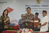 Menteri Keuangan Sri Mulyani (kiri), Bupati Banyuwangi Azwar Anas (kedua kiri) dan Sekda Provinsi Bali Dewa Made Indra (kedua kanan) menyaksikan penandatanganan oleh Sekretaris Jenderal Kemenkeu Hadiyanto (tengah) dan Gubernur Bali I Wayan Koster (kanan) tentang Hibah Laptop dan Printer, di Denpasar, Bali, Kamis (25/10/2018). Kementerian Keuangan menghibahkan 500 unit laptop dan 300 unit printer yang digunakan pada Pertemuan Tahunan IMF-World Bank Group 2018, kepada institusi pendidikan di Provinsi Bali, Provinsi NTB dan Kabupaten Banyuwangi. ANTARA FOTO/Fikri Yusuf/wdy/2018