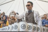 Gubernur Provinsi Jawa Barat Ridwan Kamil (kedua kanan) menyeduh kopi untuk dibagikan kepada warga pada Festival Ngopi Saraosna Volume 6 di halaman Gedung Sate, Bandung, Jawa Barat, Jumat (12/10). Festival tersebut menampilkan sedikitnya 20 jenis Kopi khas Jawa Barat yang siap diperkenalkan dan disajikan kepada masyarakat serta kegiatan konvoi motor (City Riding) juga lelang barang untuk donasi korban bencana alam di Palu dan Donggala, Sulawesi Tengah. ANTARA FOTO/Novrian Arbi/ama/18