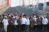 Presiden Joko Widodo (tengah) didampingi Ibu Negara Iriana Joko Widodo  (ketujuh kanan) dan Gubernur Jawa Timur Soekarwo (delapan kiri) serta sejumlah ulama berjalan di atas Jembatan Suramadu di sela-sela peresmian pembebasan tarif tol Jembatan Suramadu di Surabaya, Jawa Timur, Sabtu (27/10/2018). Dengan diberlakukan pembebasan tarif tol tersebut diharapkan berdampak pada pertumbuhan ekonomi di Pulau Madura. Antara Jatim/Zabur Karuru