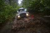 Kendaraan 4x4 melewati kubangan lumpur saat membawa peserta untuk berwisata 