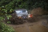 Kendaraan 4x4 melewati kubangan lumpur saat membawa peserta untuk berwisata 