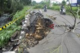 Pengguna jalan melintas di dekat jalan yang mengalamo longsor di Cibeureum RT 01/08, Kelurahan Mulyaharja, Kota Bogor, Jawa Barat, Senin (12/11/18). Intensitas curah hujan yang tinggi di wilayah Kota Bogor pada Minggu (11/11/18) sore mengakibatkan sebagian bahu jalan tersebut mengalami longsor dan mengganggu aktivitas akses jalan warga. ANTARA JABAR/Arif Firmansyah/agr.