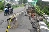 Pengguna jalan melintas di dekat jalan yang mengalamo longsor di Cibeureum RT 01/08, Kelurahan Mulyaharja, Kota Bogor, Jawa Barat, Senin (12/11/18). Intensitas curah hujan yang tinggi di wilayah Kota Bogor pada Minggu (11/11/18) sore mengakibatkan sebagian bahu jalan tersebut mengalami longsor dan mengganggu aktivitas akses jalan warga. ANTARA JABAR/Arif Firmansyah/agr.