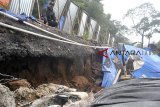 Warga melihat jalan retak di Riung Gunung, Desa Tugu Selatan, Cisarua, Kabupaten Bogor, Jawa Barat, Kamis (29/11). Jalan retak di sebagian badan jalan di lokasi perbaikan longsor jalur Puncak, Bogor tersebut akibat curah hujan yang tinggi sehingga lalu lintas kendaraan hanya dapat digunakan satu lajur secara bergantian. ANTARA JABAR/Arif Firmansyah/agr.