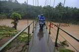 Warga melintasi jembatan gantung di Desa Cipatujah, Kabupaten Tasikmalaya, Jawa Barat, Rabu (7/11/2018). Akibat jembatan Pesangrahan Cipatujah tidak bisa dilalui akibat diterjang banjir bandang, sebagian warga terpaksa melewati jembatan gantung alternatif yang menghubungkan Desa Cipatujah dengan Desa Ciandum untuk beraktivitas meskipun jembatan tersebut tidak layak dilewati. ANTARA JABAR/Adeng Bustomi/agr.