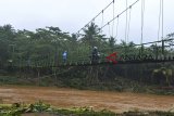 Warga melintasi jembatan gantung di Desa Cipatujah, Kabupaten Tasikmalaya, Jawa Barat, Rabu (7/11/2018). Akibat jembatan Pesangrahan Cipatujah tidak bisa dilalui akibat diterjang banjir bandang, sebagian warga terpaksa melewati jembatan gantung alternatif yang menghubungkan Desa Cipatujah dengan Desa Ciandum untuk beraktivitas meskipun jembatan tersebut tidak layak dilewati. ANTARA JABAR/Adeng Bustomi/agr.