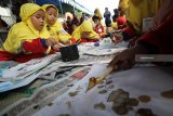 Peserta melapisi kain dengan cairan malam saat mengikuti lomba membatik di SD Muhammadiyah 11 Surabaya, Jawa Timur, Sabtu (17/11/2018). Kegiatan yang diikuti 517 pelajar tersebut bertujuan untuk menanamkan sejak dini kecintaan terhadap budaya khususnya batik. Antara Jatim/Moch Asim/ZK