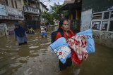 Seorang warga membawa perlengkapan tidur untuk mengungsi dari rumahnya yang terendam banjir di Kampung Bojong Asih, Dayeuhkolot, Kabupaten Bandung, Senin (12/11/2018). Banjir hingga 1,5 meter tersebut disebabkan oleh luapan Sungai Citarum serta intensitas hujan yang tinggi beberapa hari terakhir di wilayah Kabupaten Bandung. ANTARA JABAR/Raisan Al Farisi/agr.