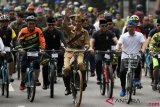     Presiden Joko Widodo (tengah) didampingi Gubernur Jawa Barat Ridwan Kamil (kanan) menyapa warga ketika mengikuti kegiatan sepeda bersama dengan tema Bandung Lautan Sepeda di Bandung, Jawa Barat, Sabtu (10/11/2018). Kegiatan yang diikuti ribuan peserta tersebut dalam rangka memperingati Hari Pahlawan. ANTARA FOTO/Wahyu Putro A/kye.