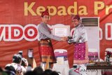 Presiden Joko Widodo (kanan) menerima piagam gelar adat kehormatan dari Gubernur Sumatera Selatan Herman Deru (kanan) saat penganugerahan gelar kehormatan adat Komering Provinsi Sumatera Selatan di halaman Griya Agung Palembang, Sumatera Selatan, Minggu (25/11/2018). Presiden Joko Widodo dianugerahi gelar kehormatan adat Komering Provinsi Sumsel yaitu Raja Balak Mangkunegara dan Ratu Indoman untuk Ibu Negara Iriana Joko Widodo. ANTARA FOTO/Nova Wahyudi/aww.