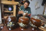 Perajin melukis motif batik gelas batok kelapa di rumah produksinya di Sukarindik, Tasikmalaya, Jawa Barat, Sabtu (3/11/2018). Dalam sehari perajin setempat mampu memproduksi satu set tempat minuman berbahan limbah batok kelapa dengan harga jual Rp250 ribu per set yang dipasarkan secara daring. ANTARA JABAR/Adeng Bustomi