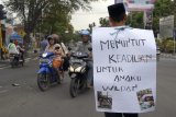 Sugiyanto (58) melakukan aksi jalan kaki dari Kota Tulungagung menuju Kota Kediri sejauh 35 kilometer sambil mengalungi poster di jalan raya Tulungagung, Tulungagung, Jawa Timur, Selasa (6/11/2018). Aksi solo itu dilakukan Sugiyanto sebagai bentuk protes atas kasus malpraktek penyuntikan vaksin MR (Measles and Rubella) terhadap anaknya, Wildan (12), yang mengalami kelumpuhan kaki total pascaimunisasi pada 23 Oktober 2018 di MTS Lirboyo, Kediri. Antara Jatim/Destyan Sujarwoko/ZK