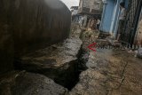 Warga beraktivitas di dekat retakan tanah di bantaran Sungai Cikapundung Kolot, Bandung, Jawa Barat, Sabtu (10/11/2018). Sedikitnya dua rumah warga mengalami kerusakan akibat tanah ambles dan rubuhnya kirmir (dinding pembatas ) sungai sepanjang 27 meter yang terjadi saat intensitas curah hujan yang tinggi beberapa waktu lalu. ANTARA JABAR/Novrian Arbi/agr.