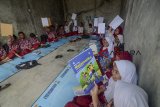 Murid SDN Dayeuhkolot 7 menunjukan soal Ujian Akhir Sekolah (UAS) di garasi mobil di Dayeuhkolot, Kabupaten Bandung, Jawa Barat, Jumat (30/11/2018). Murid SDN Dayeuhkolot 7 terpaksa melakukan UAS di garasi mobil akibat sekolahnya terendam banjir luapan Sungai Citarum. ANTARA JABAR/Raisan Al Farisi/agr.