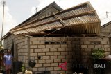Seorang wanita berdiri di samping rumahnya yang atapnya hampir rubuh diterjang oleh angin di Kota Kupang, NTT, Senin (12/11/2018). Badan Penangulangan Bencana Daerah (BPBD) NTT mendata kurang lebih tujuh rumah mengalami kerusakan berat serta satu SPBU ambruk diterjang badai yang disertai hujan lebat yang terjadi pada Minggu (11/11) malam. Antara Foto/Kornelis Kaha.