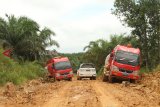 Sebuah mobil melintasi dua truk tangki Bahan Bakar Minyak (BBM) milik PT Pertamina  mangkrak di dalam tanah berlumpur di Dusun Tapang Kabang, Desa Malenggang, Kecamatan Sekayam, Kabupaten Sanggau, Kalimantan Barat, Kamis (15/11/2018). Jalan kubangan berlumpur sepanjang 60 kilometer yang berbatasan dengan Malaysia tersebut, menjadi jalur lintasan untuk mengantar pasokan BBM Satu Harga ke SPBU Kompak di Kecamatan Ketungau Hulu, Kabupaten Sintang, Kalbar. ANTARA FOTO/HS Putra/jhw