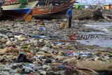 Nelayan menyandarkan perahunya di bibir pantai yang dipenuhi sampah plastik di Desa Dadap, Indramayu, Jawa Barat, Senin (26/11/2018). LSM World Wild Fund for Nature (WWF) Indonesia menilai masalah pencemaran sampah plastik di laut Indonesia sudah bisa disebut sebagai darurat sampah plastik karena perlu penanganan serius. ANTARA JABAR/Dedhez Anggara/agr.