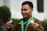 Lifter Eko Yuli Irawan memperlihatkan medali seusai diterima oleh Presiden Joko Widodo di Kompleks Istana Kepresidenan, Jakarta, Kamis (8/11/2018). Presiden mengapresiasi prestasi Eko Yuli yang berhasil meraih medali emas di nomor 61 kg serta memecahkan rekor dunia untuk total angkatan 317 kg dan angkatan clean and jerk 174 kg pada kejuaraan dunia angkat besi di Ashgabat, Turkmenistan. Antara Foto/Wahyu Putro A